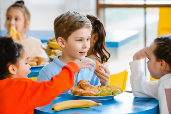 preschool aged children eating  at a table